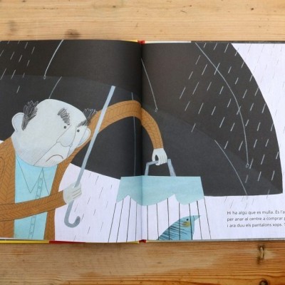 Livro aberto com ilustração de homem a chorar sob chuva e texto em português