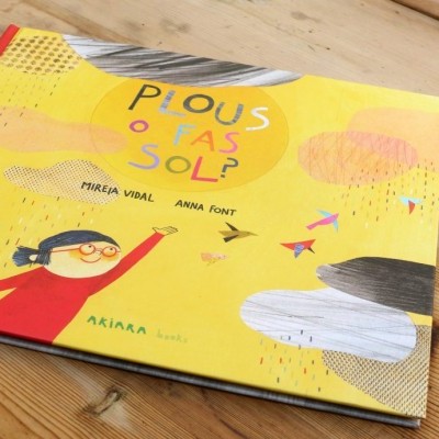 Livro infantil com capa amarela e lombada vermelha sobre mesa de madeira