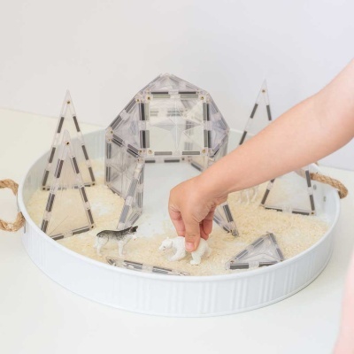 Blocos magnéticos transparentes formando estruturas em banda branca com areia e figuras de animais.