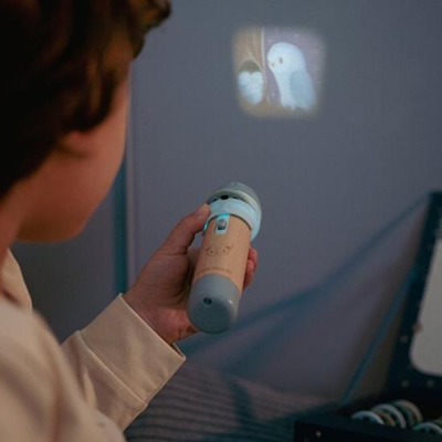 Criança a usar projetor portátil que exibe personagens animados na parede