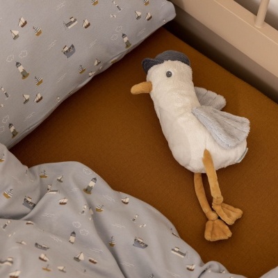 Cama de criança com edredom azul claro decorado com gansos e boneco de peluche de ganso