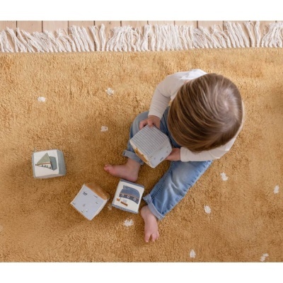 Criança sentada em tapete castanho claro com blocos de madeira coloridos
