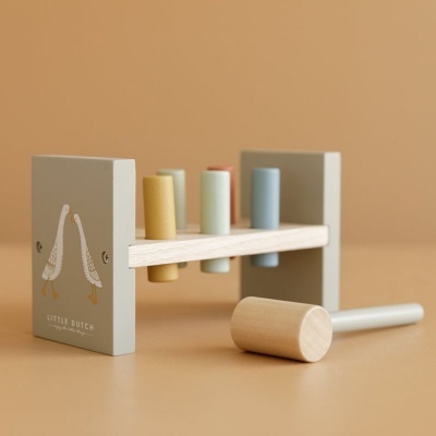 Brinquedo infantil de madeira com martelo e cilindros coloridos em fundo bege