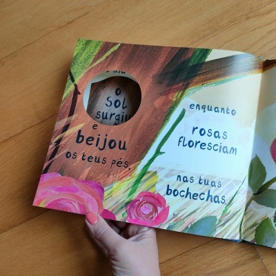 Livro infantil aberto com ilustrações de rosas e texto em português