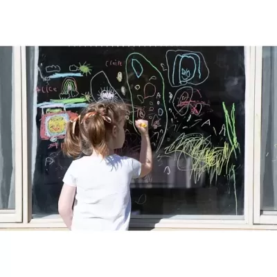 Criança a desenhar num quadro negro com giz colorido