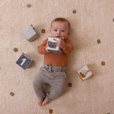 Bebé deitado num tapete com cubos de tecido ao redor.