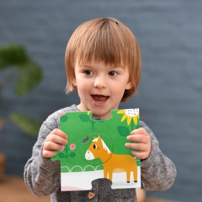 Criança a segurar peça de puzzle com cavalo amarelo em fundo verde