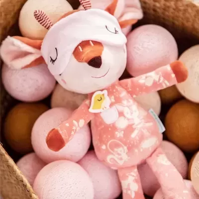 Boneco de pelúcia rosa em forma de veado numa cesta com bolas decorativas