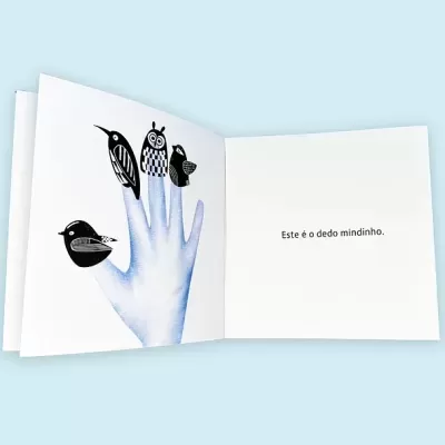 Livro infantil aberto com mão azul e dedos com pássaros, texto em português