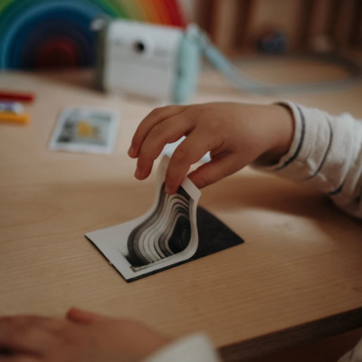 Criança a folhear um livro preto e branco numa mesa de madeira
