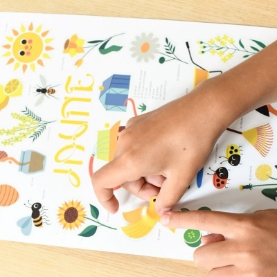 Livro infantil colorido com ilustrações de flores e insetos e mão de criança apontando