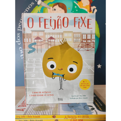 Capa do livro 'O Feijão Fixe' com ilustração de feijão amarelo e fundo de números e casas desenhadas.