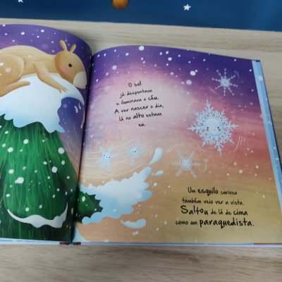 Livro infantil aberto com esquilo e flocos de neve animados em fundo colorido com texto em português europeu