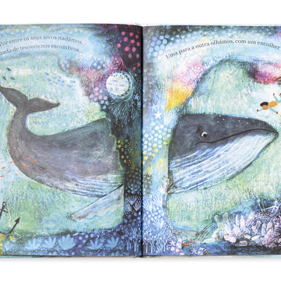Livro infantil aberto com ilustrações de baleias e elementos marinhos coloridos.