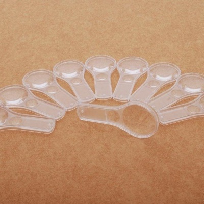 Conjunto de colheres medidoras transparentes em forma semicircular sobre fundo castanho