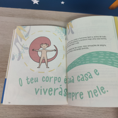 Livro aberto com ilustração de criança e texto em português sobre o corpo