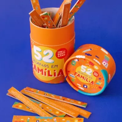 Embalagem laranja com palitos coloridos e texto 52 desafios em família