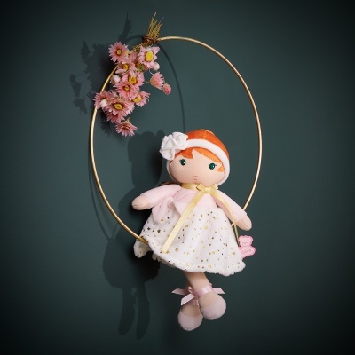 Boneca de pano com vestido branco pendurada num aro dourado com flores cor-de-rosa