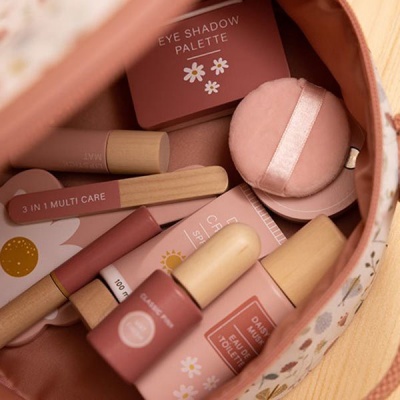 Bolsa pequena estampada com produtos de beleza em tons rosa e nude.