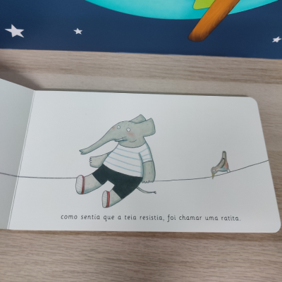 Página de livro infantil com ilustração de elefante cinzento sentado numa corda e texto em português.