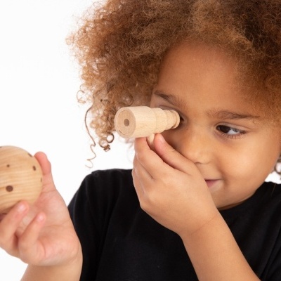 Criança a brincar com brinquedos de madeira cilíndricos e esféricos