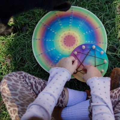 Dois instrumentos de percussão coloridos, criança tocando sentado na relva.