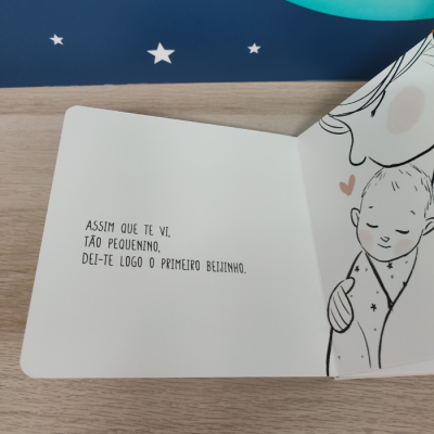 Página aberta de livro infantil com texto e ilustração a preto e branco de adulto e bebé