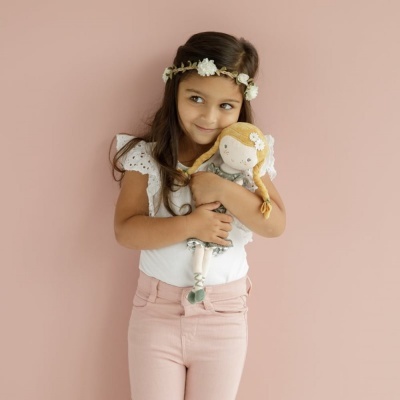 Menina com boneca de pano abraçada e coroas de flores na cabeça