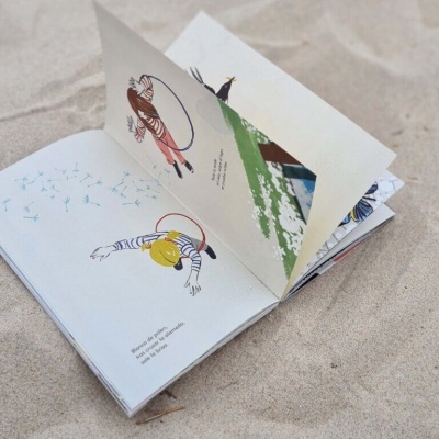 Livro ilustrado aberto sobre areia de praia