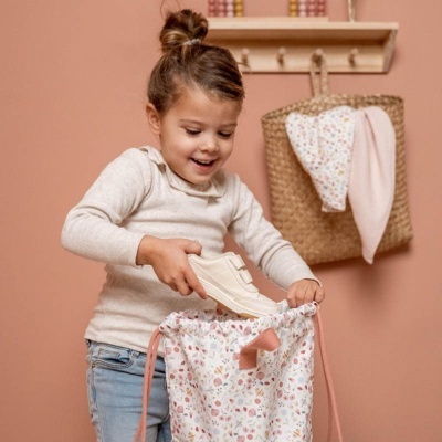 Menina a guardar sapatos brancos em saco com padrão floral