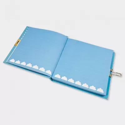 Caderno aberto azul com nuvens brancas na parte inferior e clipe metálico.