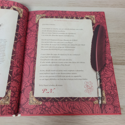 Página de livro infantil com texto em português e ilustração de pena preta sobre fundo vermelho com padrão floral.