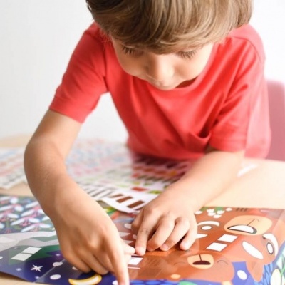 Criança a manipular livro colorido com formas e rostos desenhados