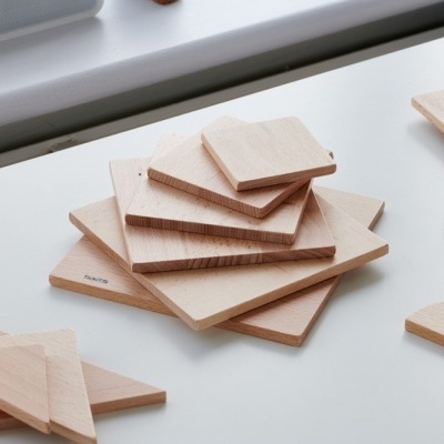 Tábuas de madeira clara empilhadas sobre superfície branca