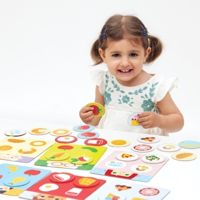 Criança a brincar com cartas coloridas de comida para atividades lúdicas.