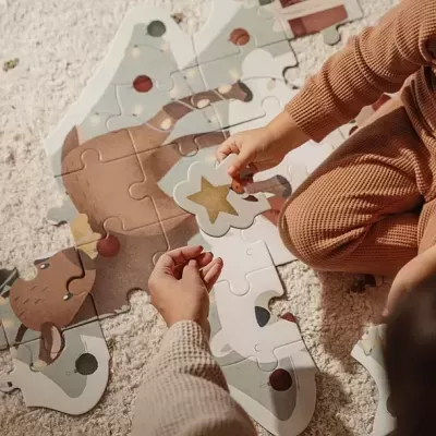 Crianças montam um quebra-cabeça grande com peça de estrela dourada sobre tapete branco