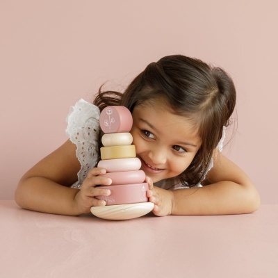 Menina a brincar com brinquedo de empilhar de madeira rosa e bege.