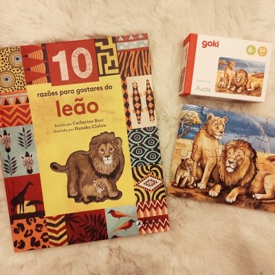 Livro educativo sobre leões e puzzle com ilustração de leões sobre tapete macio claro.