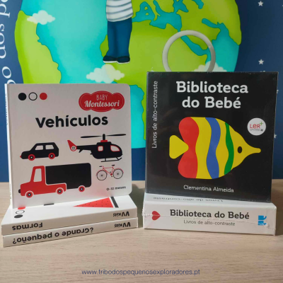 Dois conjuntos de livros para bebés, um sobre veículos e outro com peixe colorido, embalagens quadradas sobre mesa, fundo com mapa do mundo.