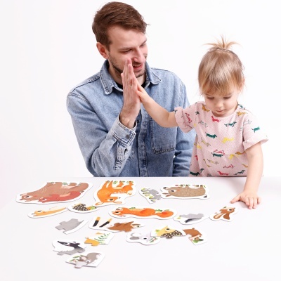 Homem e criança com puzzle de animais sobre uma mesa branca