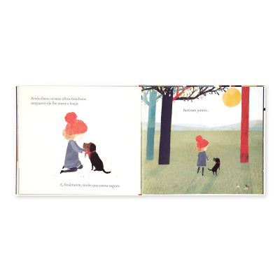 Livro ilustrado aberto com rapariga de gorro vermelho e cão preto num cenário com árvores e sol.
