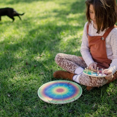 Menina sentada na relva com brinquedos coloridos de madeira