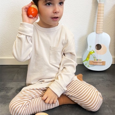 Criança sentada no chão a brincar com ovos coloridos e guitarra branca ao fundo