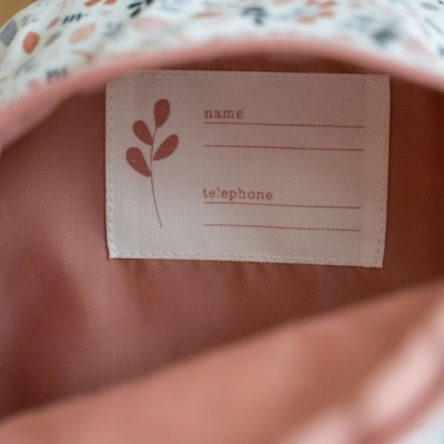 Interior de mochila floral rosa com etiqueta para nome e telefone