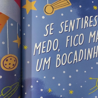 Página de livro com texto em branco e desenhos de estrelas e cometas num fundo azul.