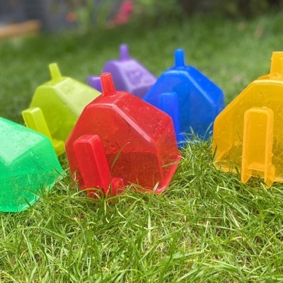 Casas de plástico coloridas translúcidas sobre relva húmida.