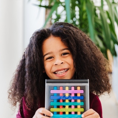 Criança sorridente a segurar jogo de tabuleiro colorido