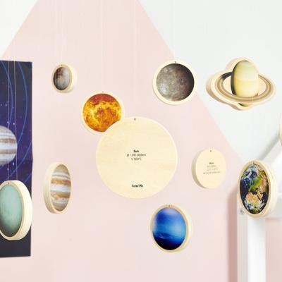 Mobile do sistema solar em madeira colorida pendurado numa sala com paredes rosa e branca