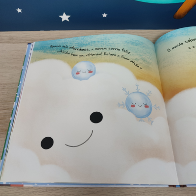 Livro infantil aberto com ilustração de nuvem sorridente e personagens azuis com texto em português.
