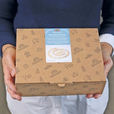 Caixa de cartão com padrão de desenhos, etiqueta azul e brinquedo de madeira ilustrado